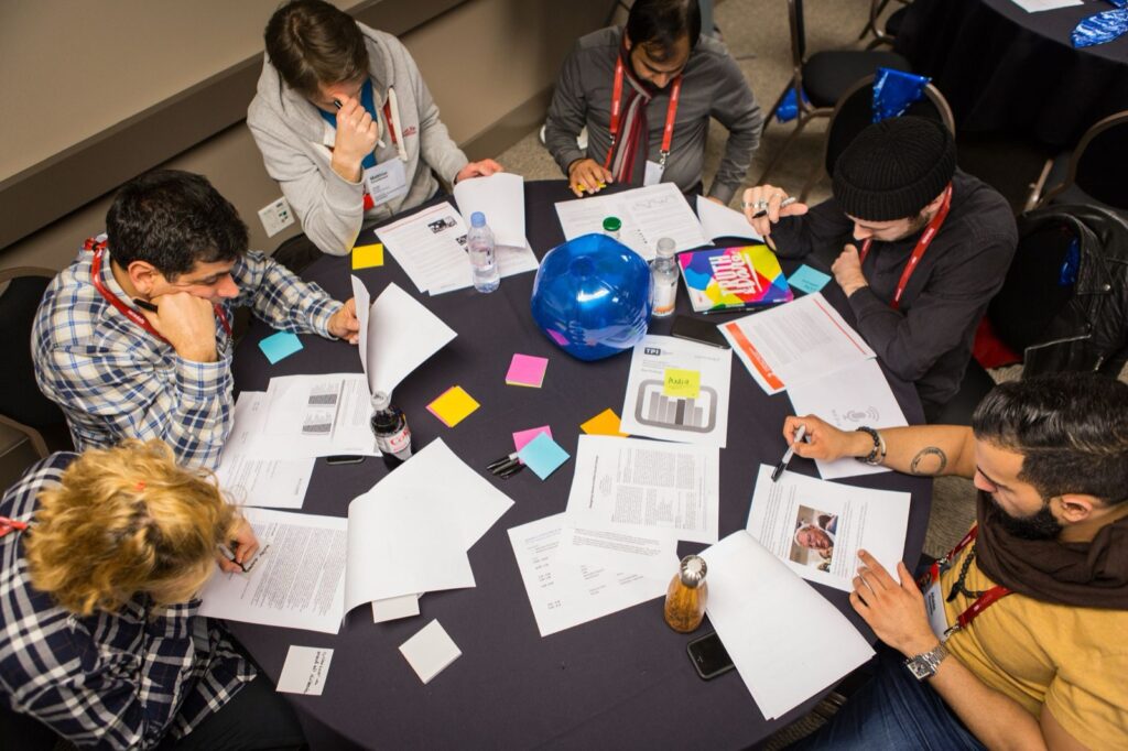 Workshop participants work through papers and sticky notes around a table