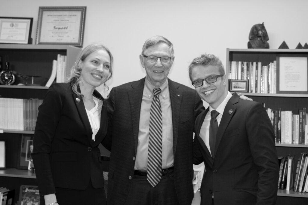 Three people pose together in an office lined with books