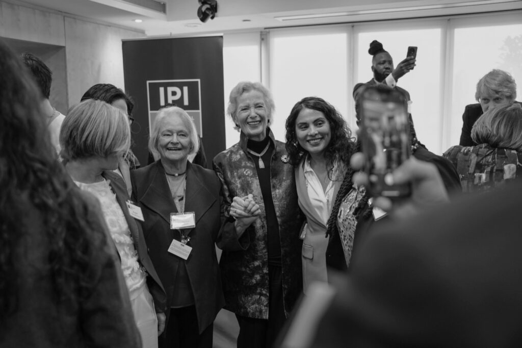 Women leaders link arms and smile at the Women Transforming Global Security launch